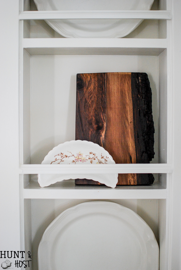 Kitchen cubbies get a makeover into a built in plate rack filled with gorgeous goodies like white and wood. White plates, cutting boards and antique tea and coffe pots. This simple DIY will help you transform small shelves into functional display space. 