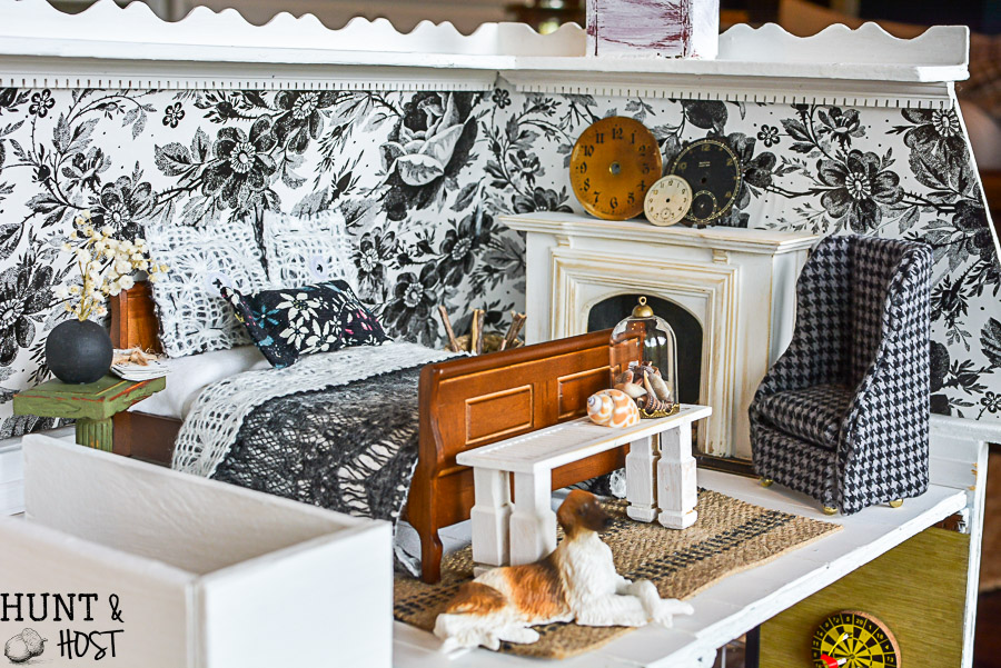 Get lost in in cozy comfort with these dollhouse master bedroom decor ideas. Large scale floral wallpaper make the room a dramatic room with vintage touches, you'll seriously want to move into this dollhouse bedroom! Vintage clocks on the fireplace mantel with a dramatic black and white theme.