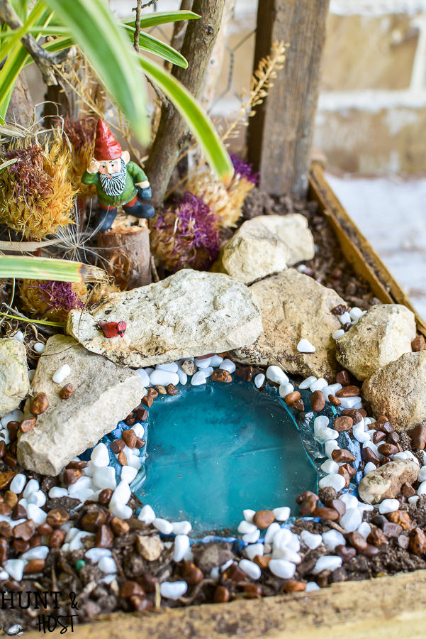 Take your fairy garden vertical with this natural fairy garden setting, complete with an actual fairy garden and swimming hole. This fun summer project to do with the kids will get your creativity going and green thumb working. Make a mini fairy garden for your house or porch with these precious fairy supplies and easy miniature ideas!