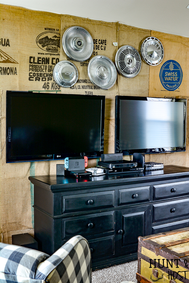 What a great game room idea! This rustic cabin lodge game room has great decorating ideas, a tutorial on how to hang a wall mounted TV (or two for a Fortnight lover's paradise!) plus an inexpensive DIY burlap wall covered in coffee bean sacks. All the elements for the perfect family game room with a cozy cabin style! #SANUS #SANUSspaces @SANUS @SANUSsystems #gameroomideas #burlapwalls #DIYwallpaper #mediaroom #TVmount #rusticroom #familyroomideas #rusticdecorideas